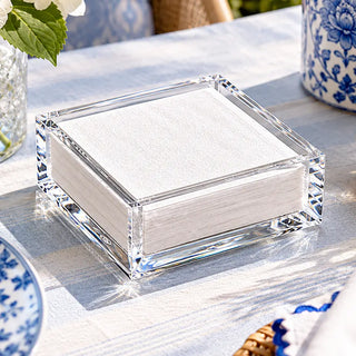 a clear box with white paper napkins on a table