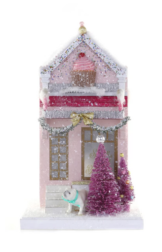 a pink house with a cupcake and trees