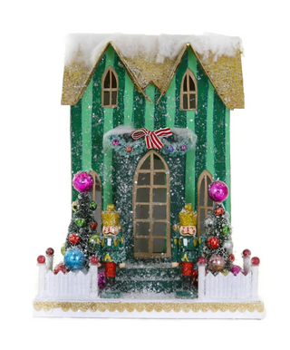 a toy house with a white fence and a green striped building